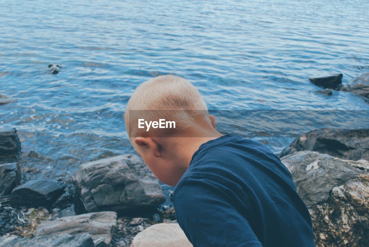 High angle view of boy on rock by sea