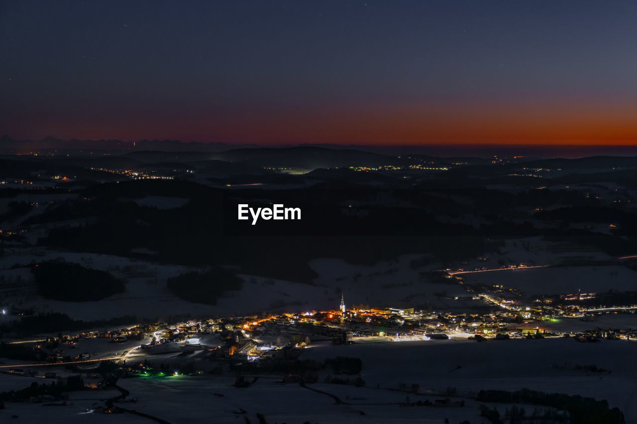 High angle view of illuminated city against sky at sunset