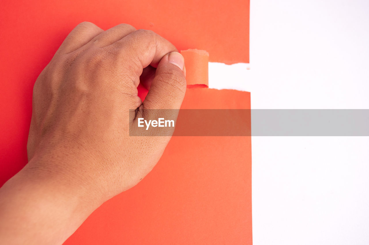 CLOSE-UP OF HUMAN HAND AGAINST RED BACKGROUND