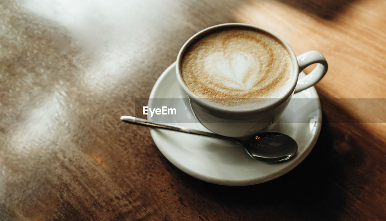 mug, coffee, cup, drink, coffee cup, food and drink, refreshment, crockery, saucer, spoon, eating utensil, kitchen utensil, table, hot drink, frothy drink, cappuccino, wood, teaspoon, still life, cafe, indoors, café au lait, coffee milk, latte, high angle view, newspaper, flat white, freshness, cortado, no people, close-up, food, tableware, coffee break, froth art, heat