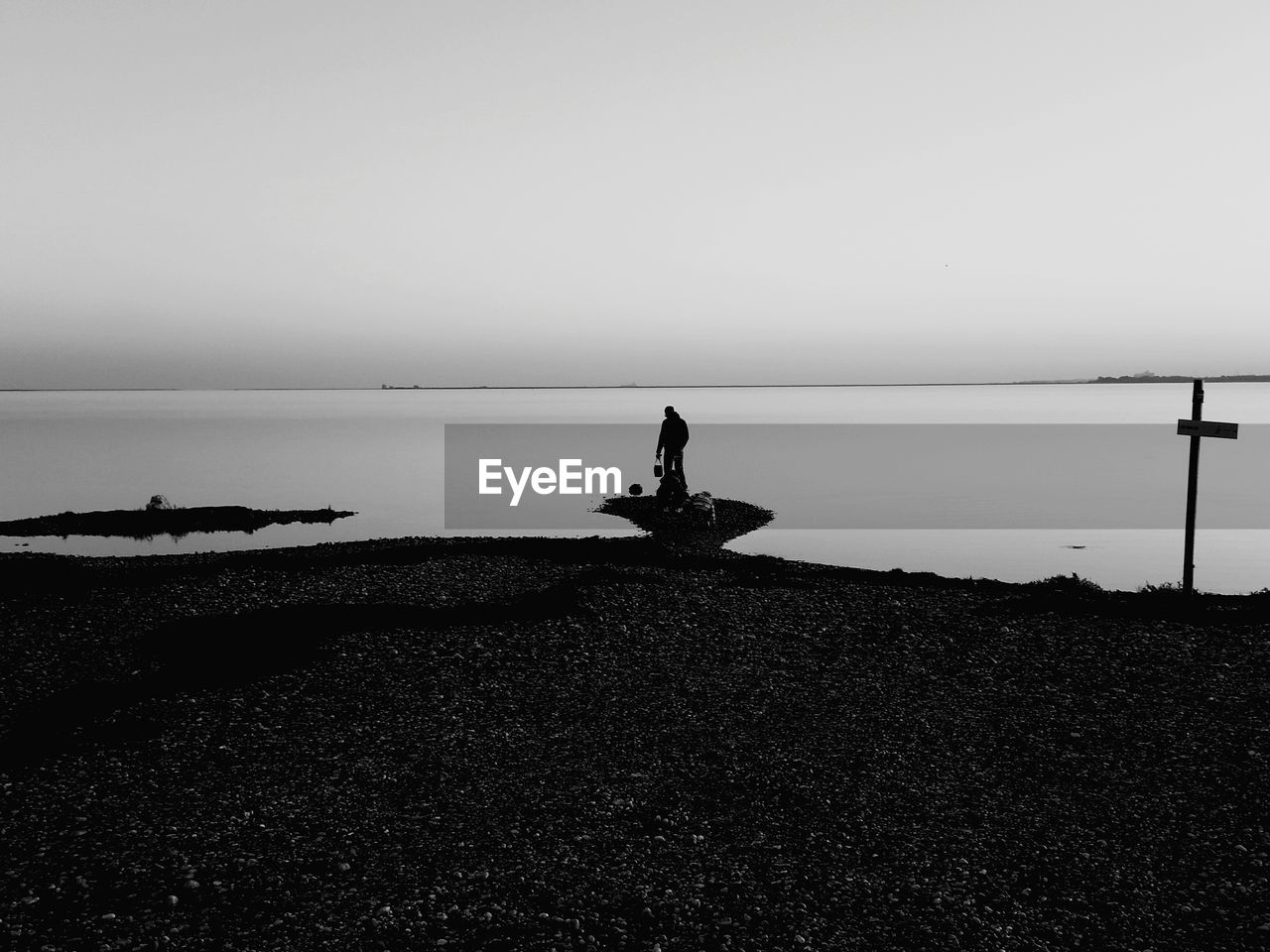 MAN STANDING ON BEACH AGAINST SKY