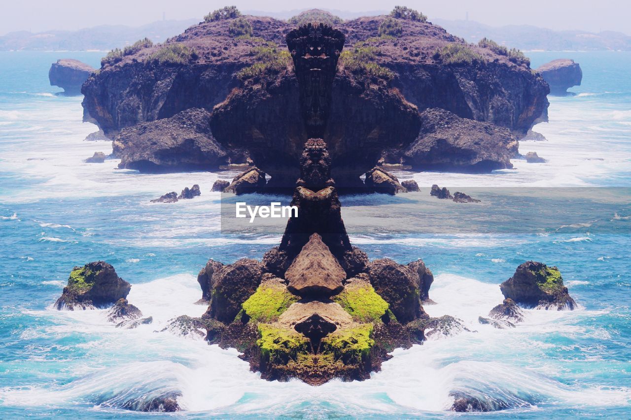 Digital composite of rock formation in sea against sky