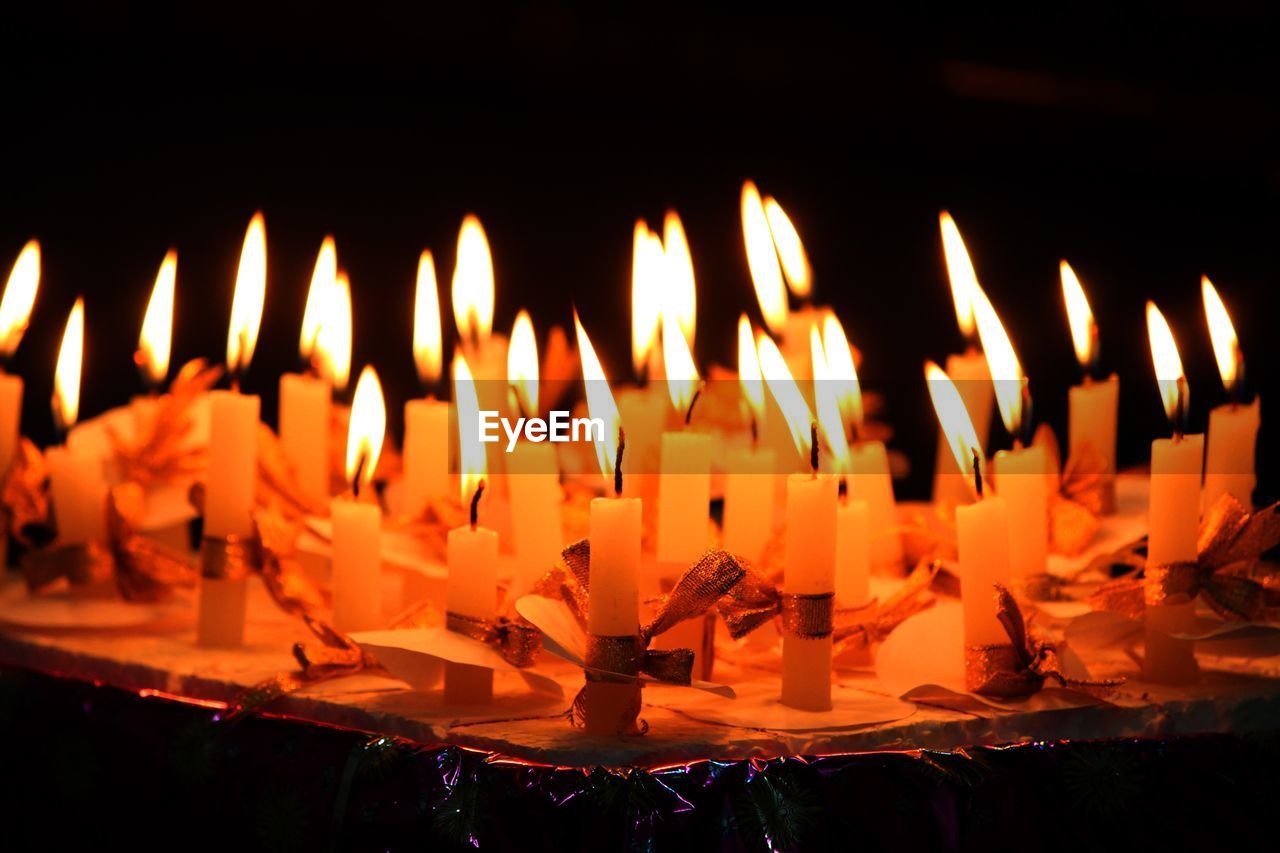 Close-up of lit candles on table in darkroom