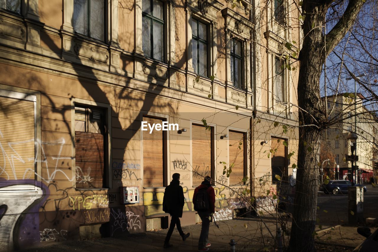 PEOPLE WALKING ON STREET AMIDST BUILDINGS