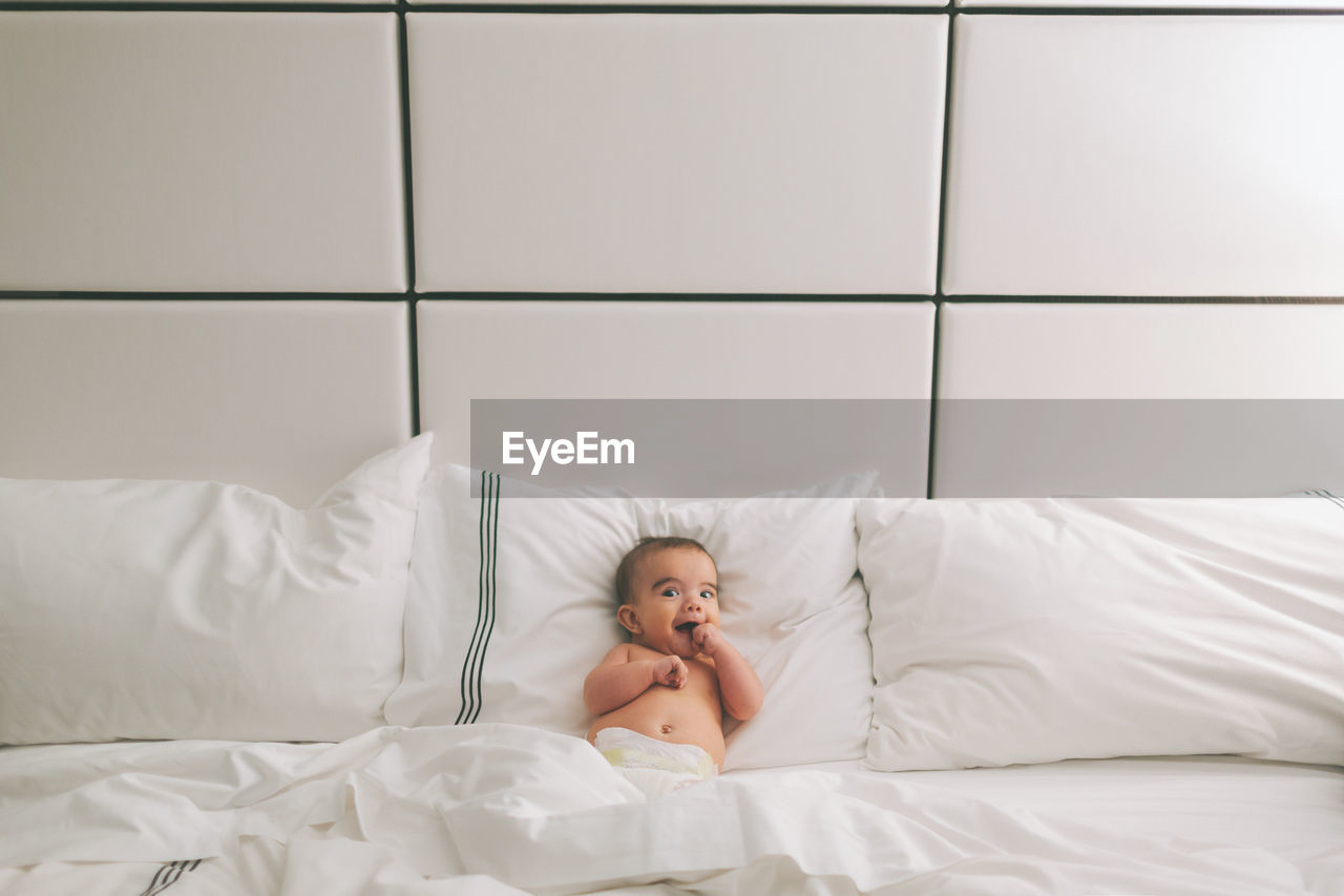 Portrait of baby boy lying on bed at home