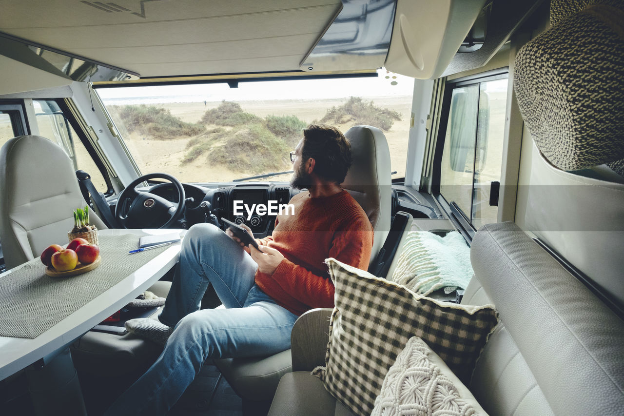 Mature man with digital tablet sitting in motor home on vacation