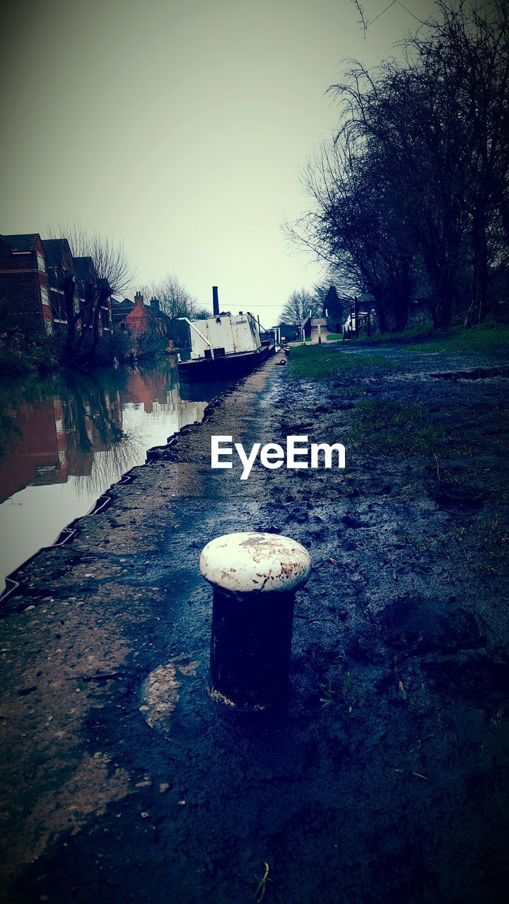 Bollard by canal against clear sky