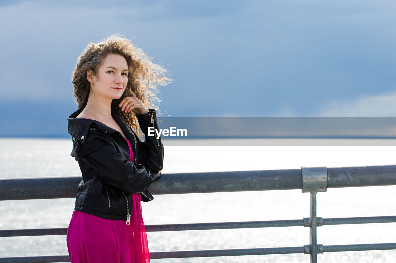 A woman stands on a bridge against the background of a gloomy sky