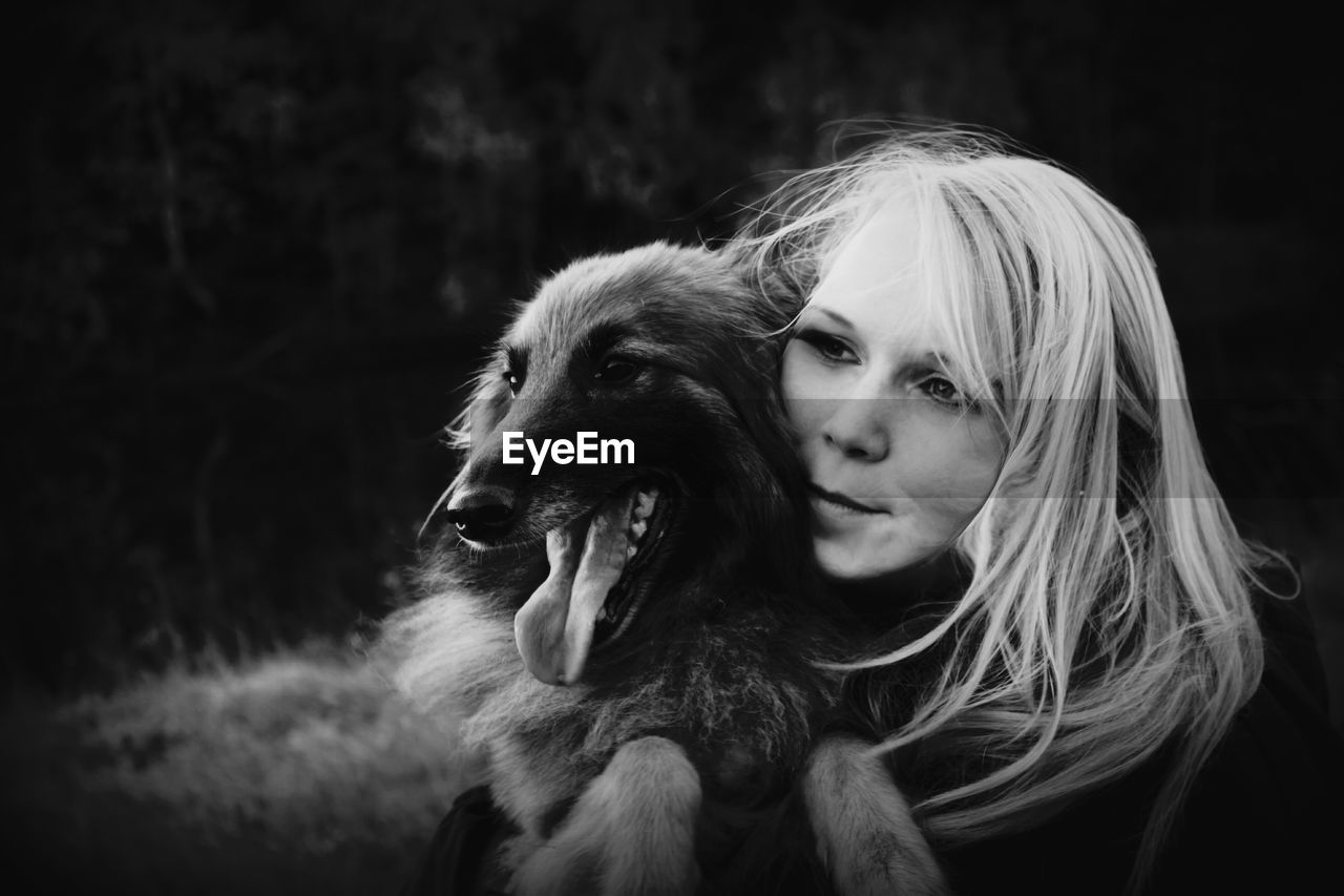 Close-up of young woman embracing dog on field