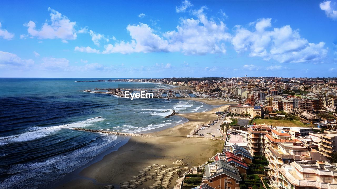 AERIAL VIEW OF SEA AND BUILDINGS AGAINST BLUE SKY