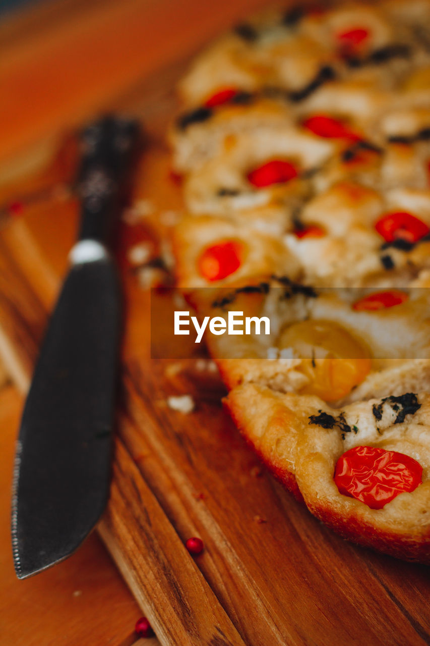 Close-up of food on table. homemade italian focaccia, with tomato, pink pepper and olive oil.