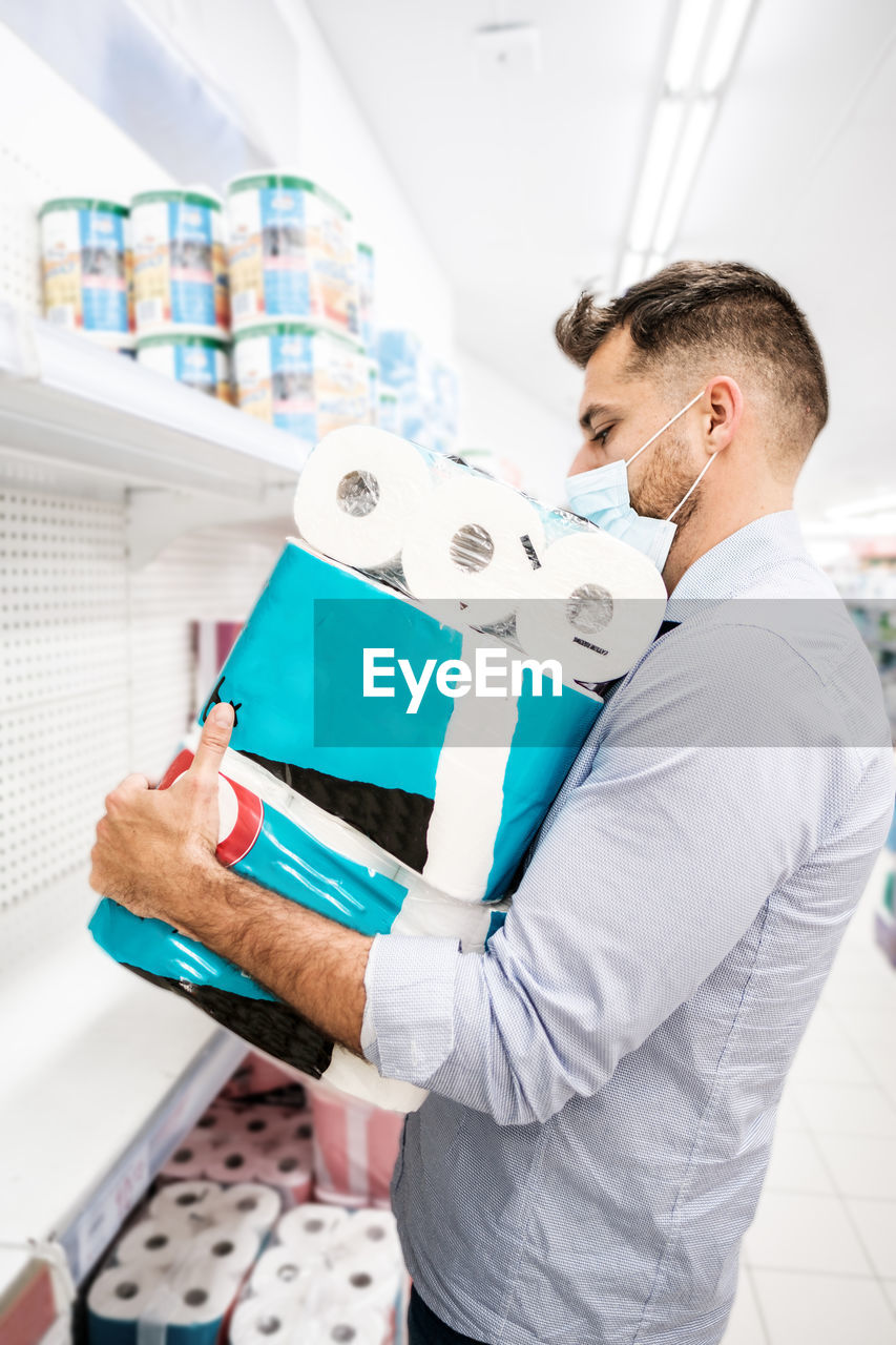 A man is panic buying toilet paper in the supermarket. stock piling toilet paper rolls 