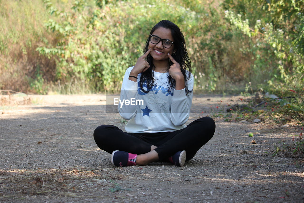 Portrait of young woman sitting on land outdoors