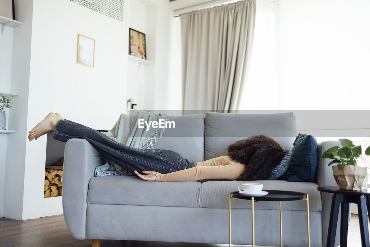 Young woman lying on sofa at home