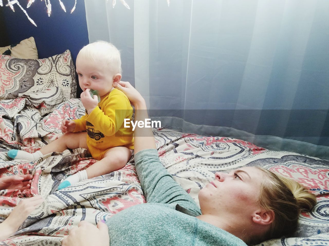 Mother touching son while lying on bed at home