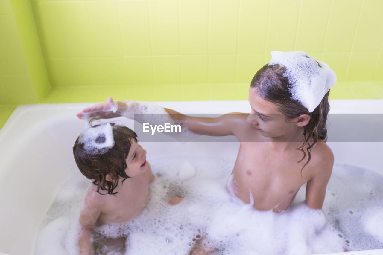 High angle view of happy siblings playing in bathtub