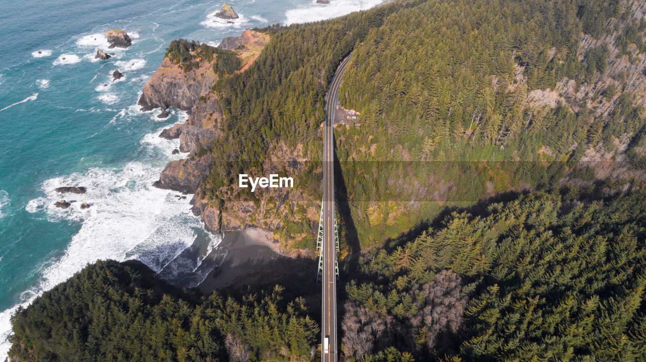 Aerial view of bridge amidst trees and mountains by sea