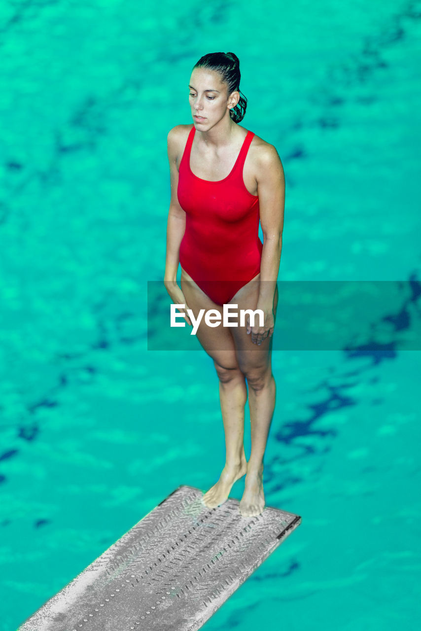 Swimmer standing on diving platform over swimming pool