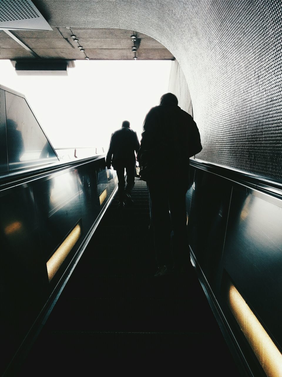 Low angle view of people walking up escalator