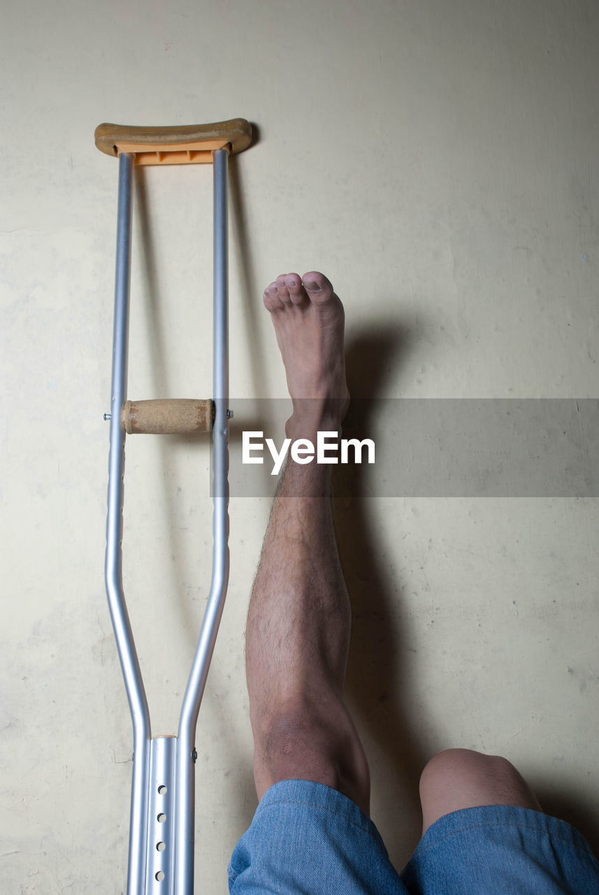 Low section of handicapped man with crutch on floor