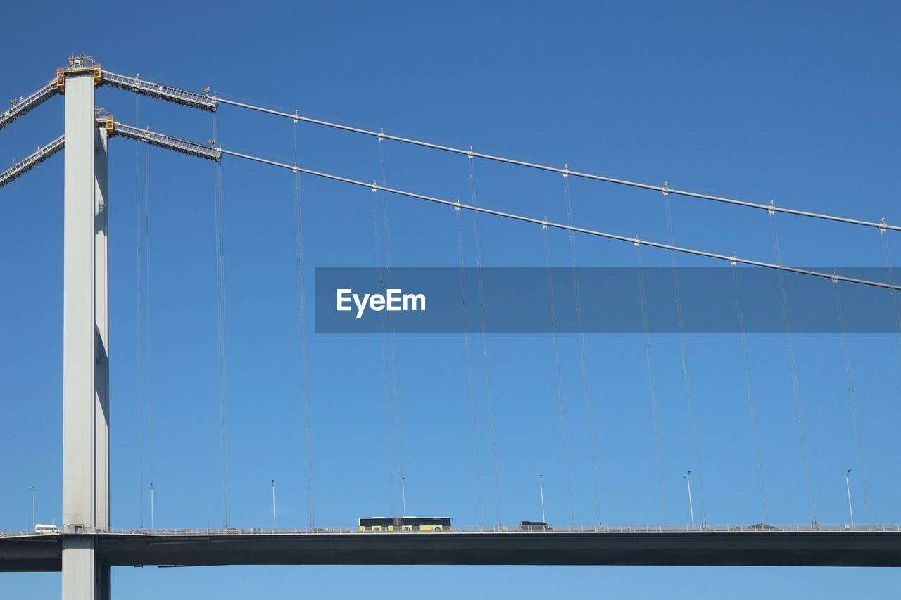 Low angle view of suspension bridge against clear blue sky