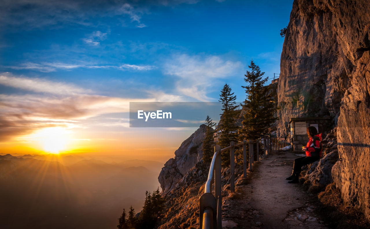 Man on mountain road against sky during sunset