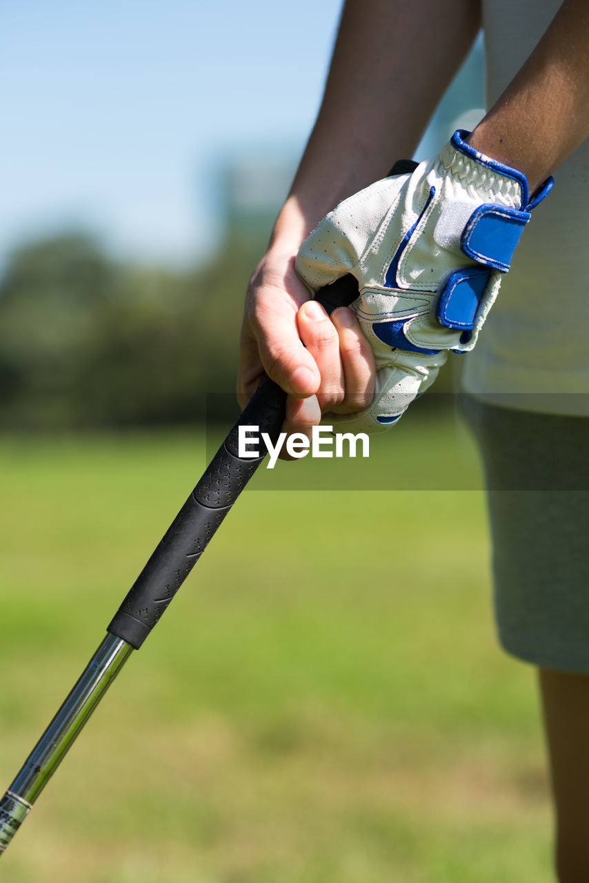 Midsection of golfer gripping golf club