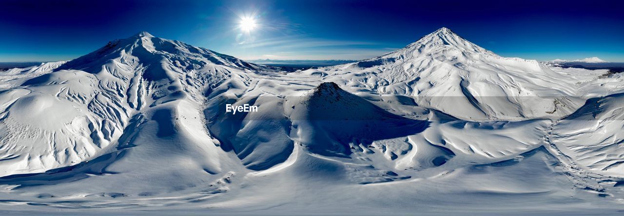 Scenic view of snowcapped mountains against blue sky