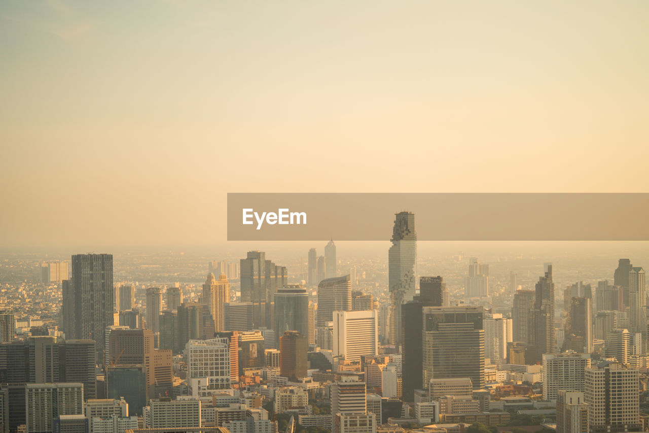 Modern buildings in city against sky at sunset