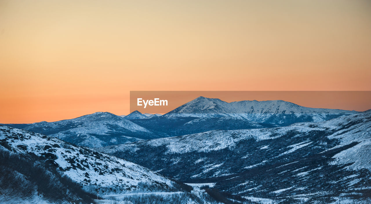 Scenic view of snowcapped mountains against sky during sunset