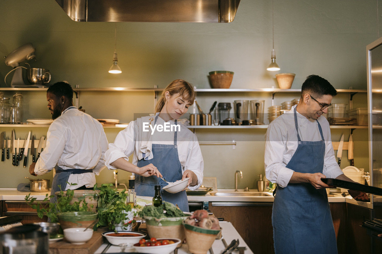 Multiracial male and female chef preparing food in commercial kitchen