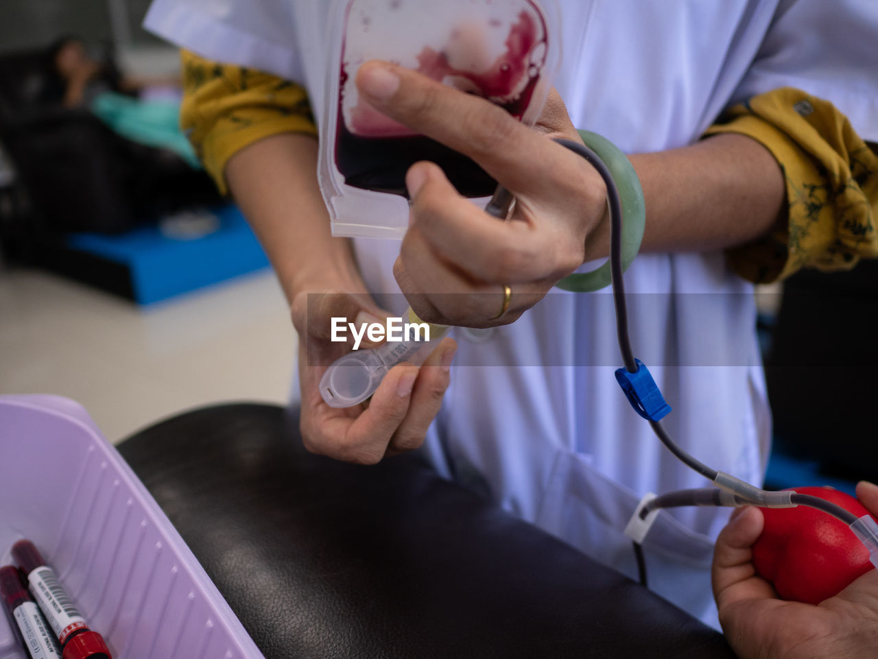 Close-up of doctor holding bag while standing by patient during donation 