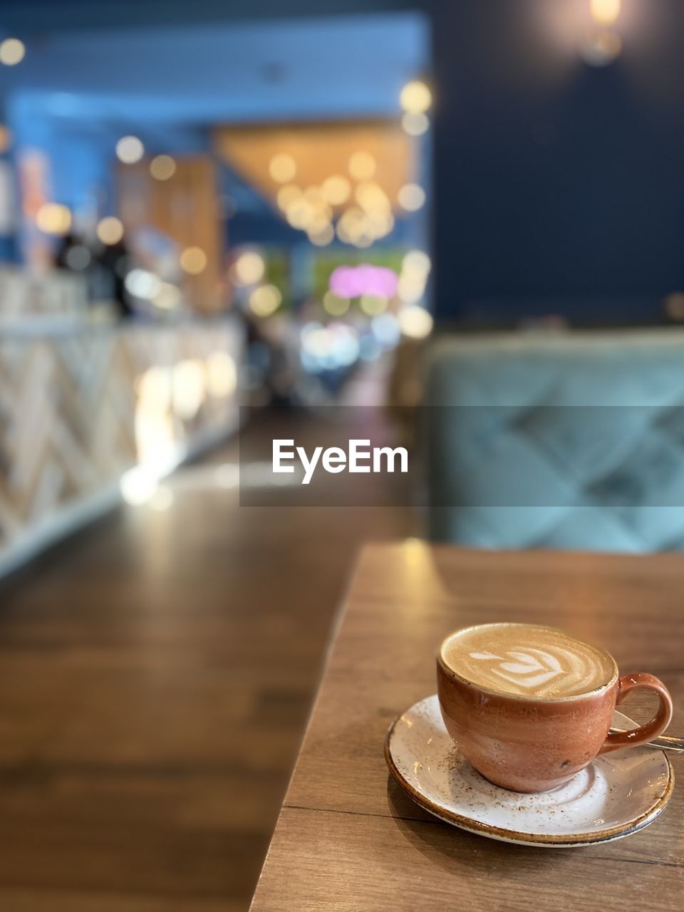 food and drink, coffee, drink, coffee cup, mug, cup, cafe, table, refreshment, focus on foreground, restaurant, business, cappuccino, hot drink, saucer, indoors, crockery, latte, no people, meal, illuminated, wood, still life, food, coffee shop, tableware, bar, selective focus