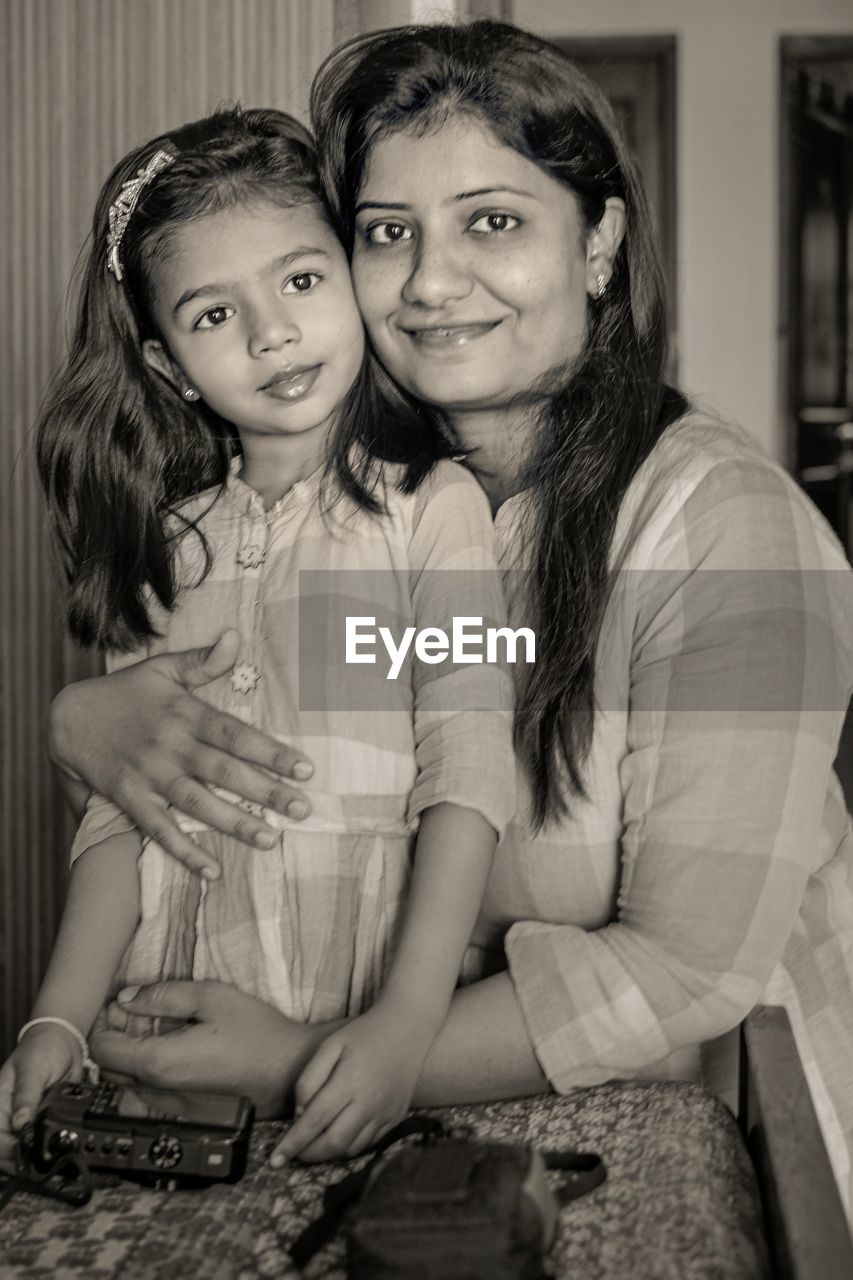 Portrait of mother and daughter sitting at home