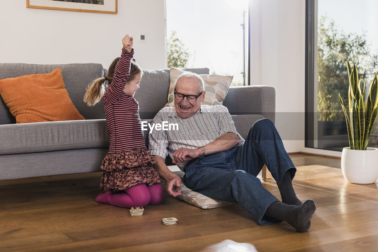 Grandfather and granddaughter playing memory, girl celebrating victory