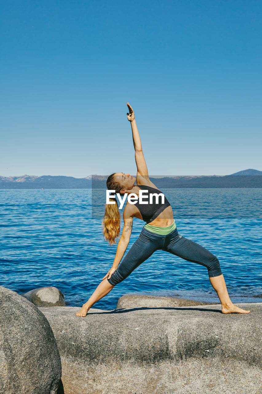 Young woman practicing yoga on lake tahoe in northern california.