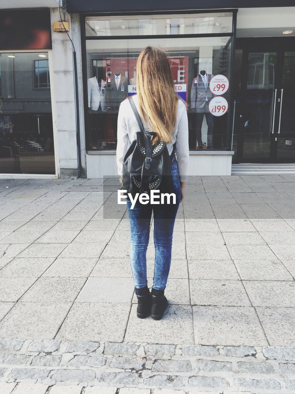 Full length rear view of woman standing in front of clothing store