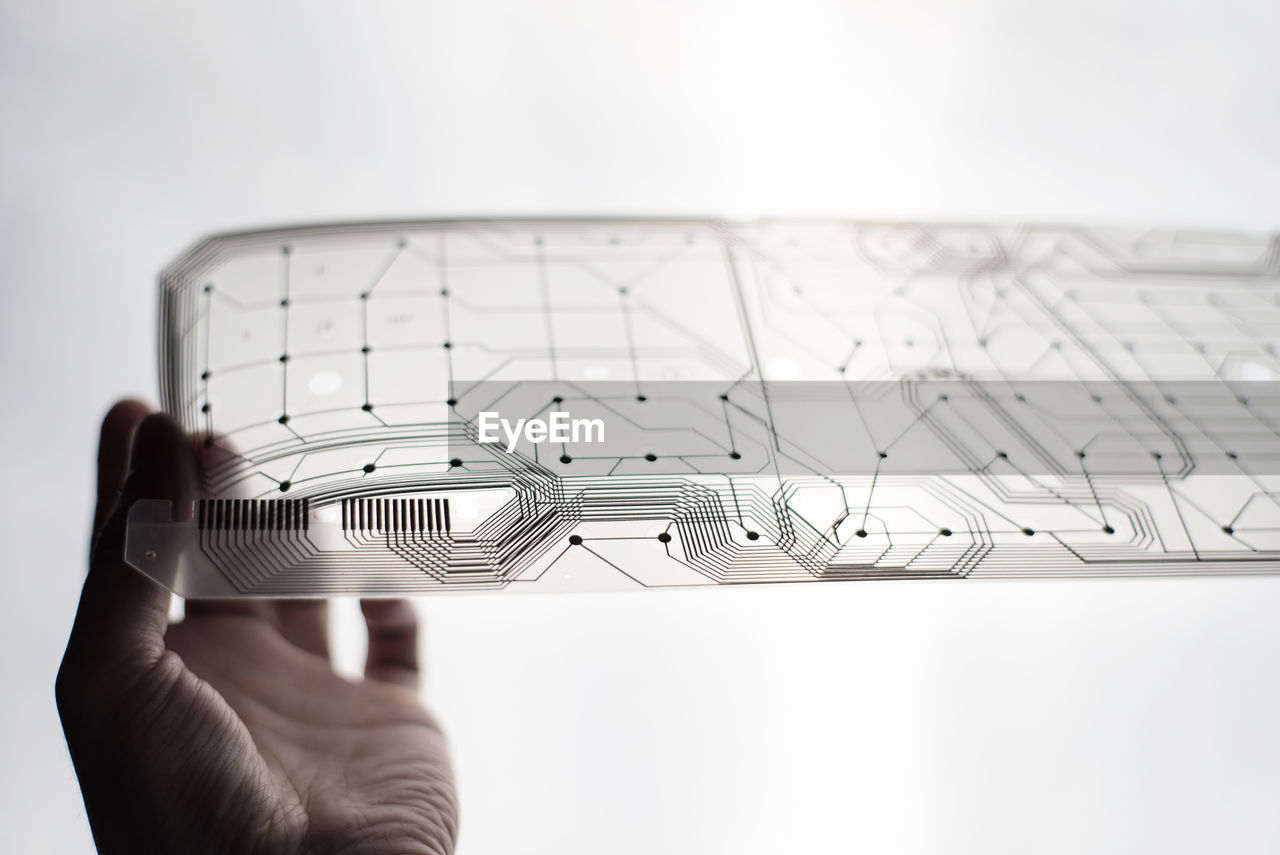 Close-up of hand holding transparent material against white background