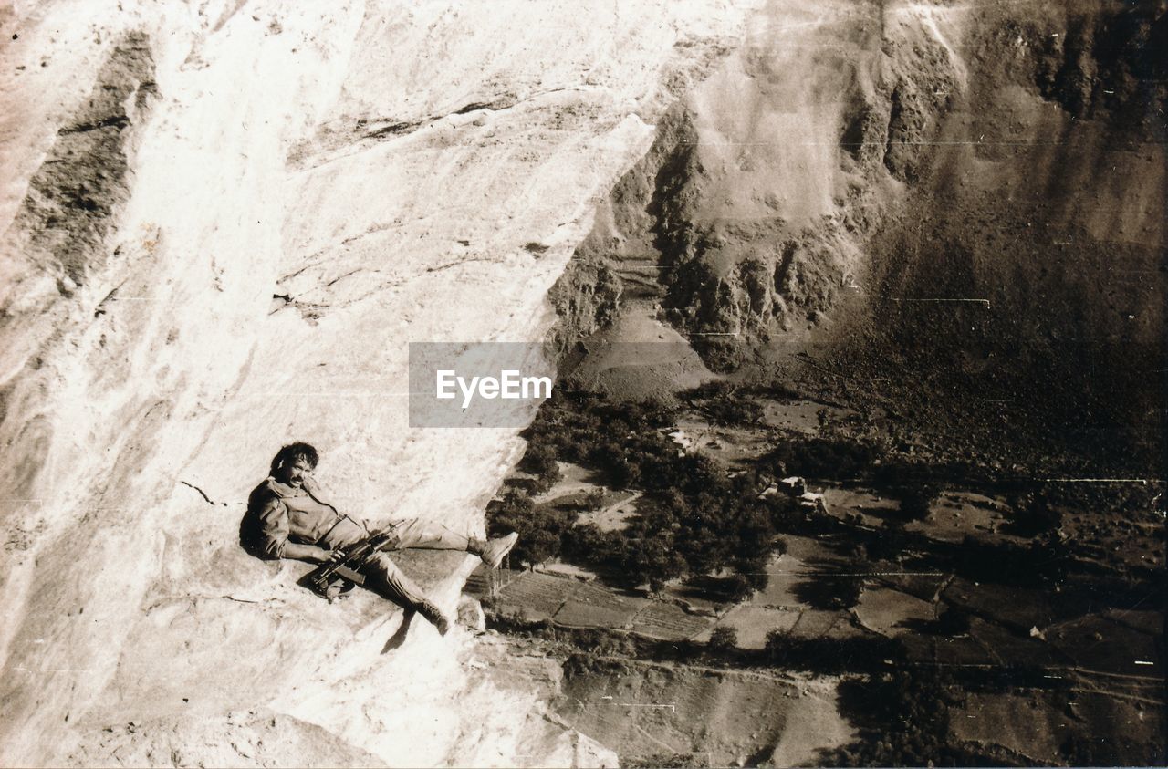 Portrait of army soldier with rifle leaning on rock