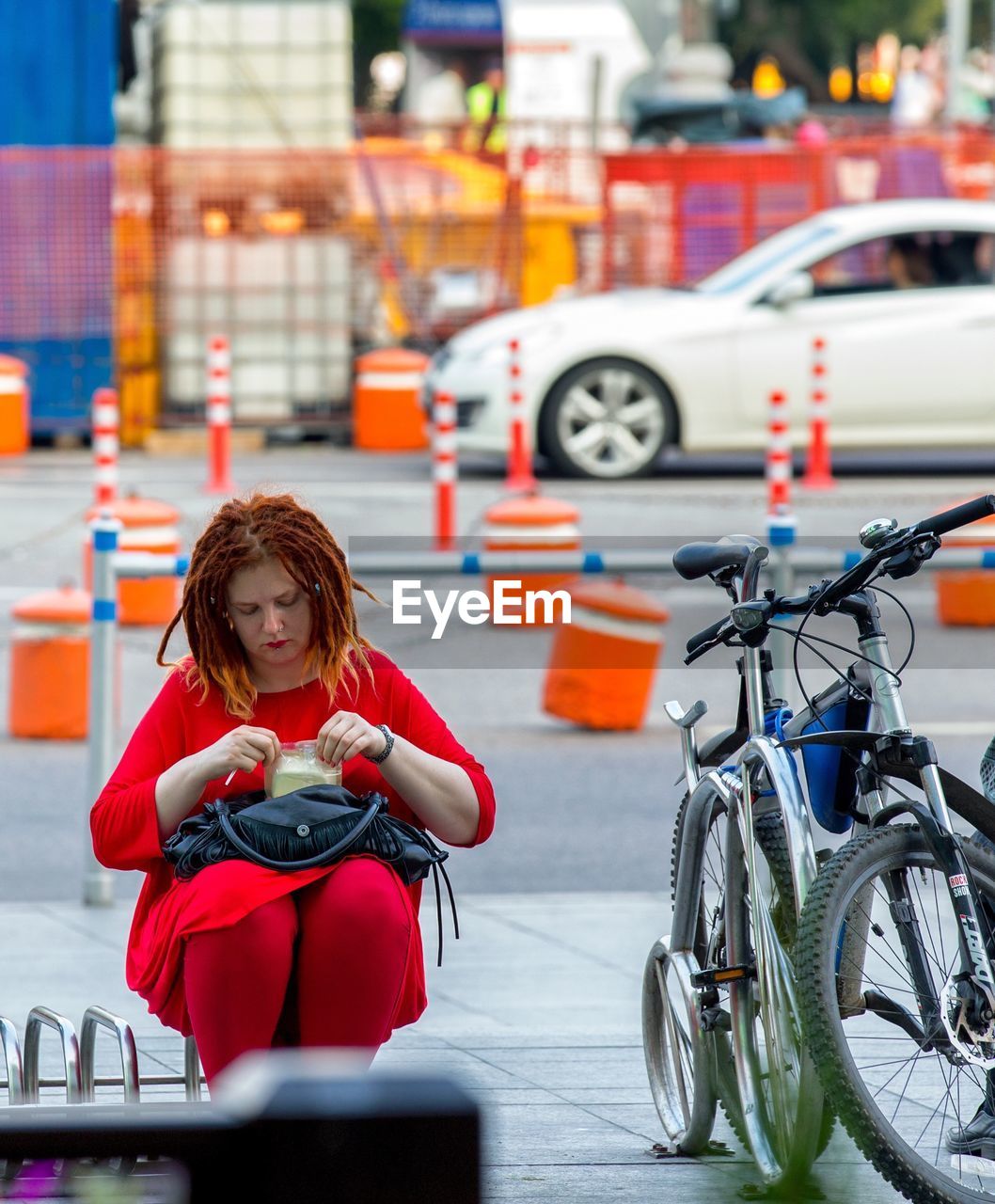 FULL LENGTH OF WOMAN WITH BICYCLE SITTING ON MOTORCYCLE