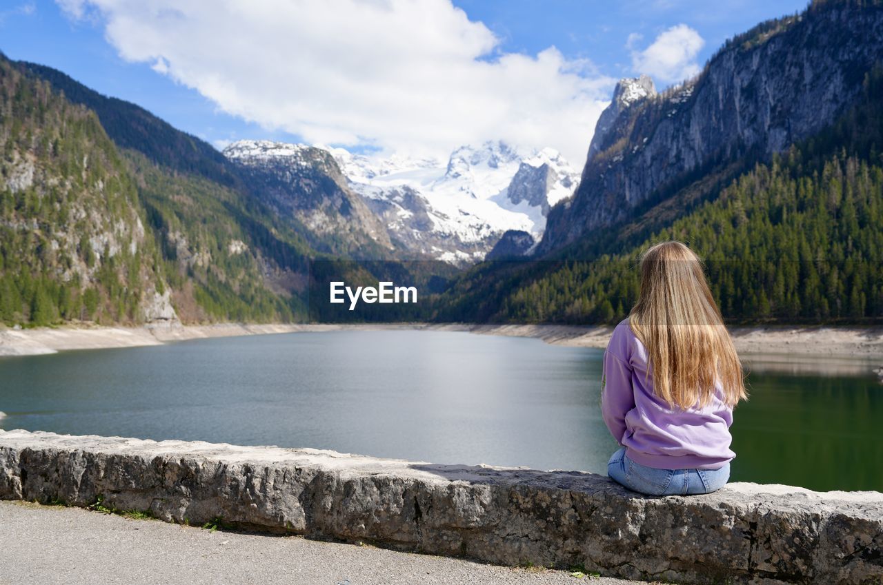 Rear view of gurl sitting by lake