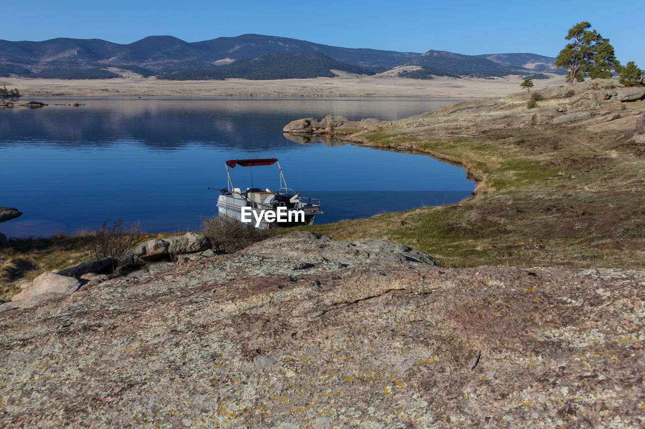 SCENIC VIEW OF LAKE BY MOUNTAIN AGAINST CLEAR SKY