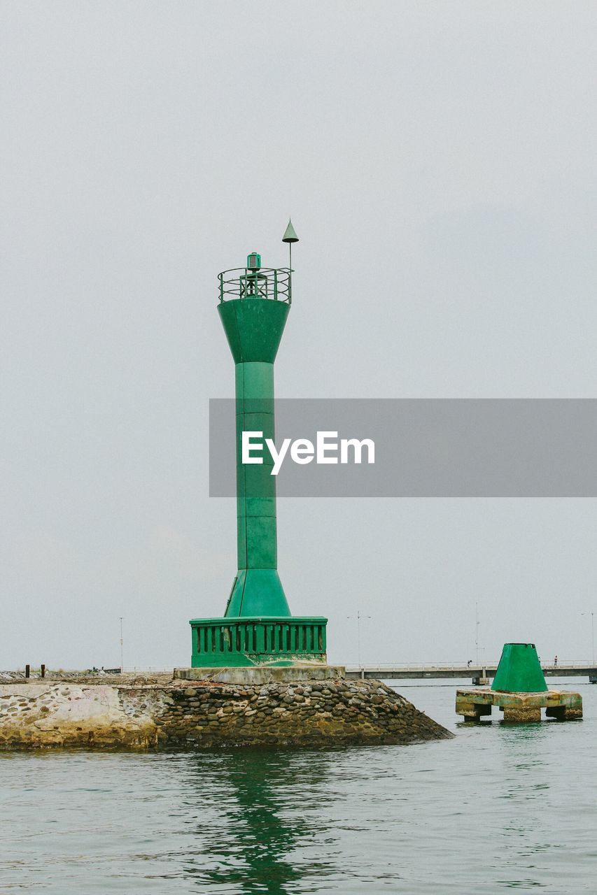 Lighthouse amidst sea against clear sky