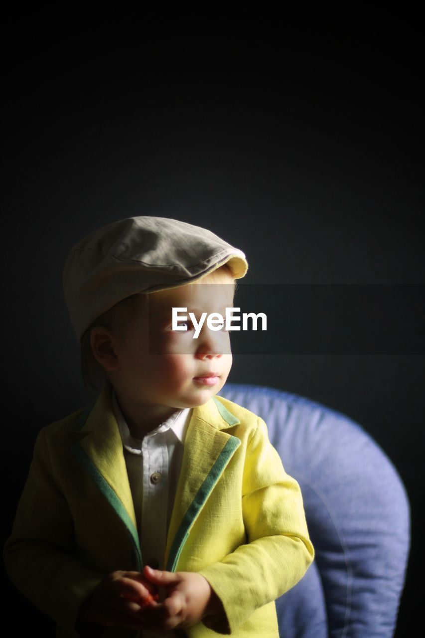 Cute baby boy standing against black background