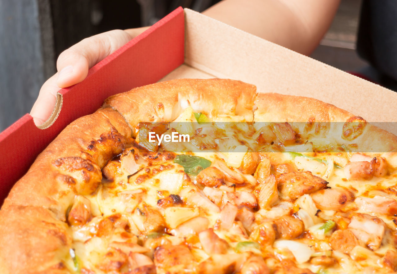 Cropped hand holding pizza box