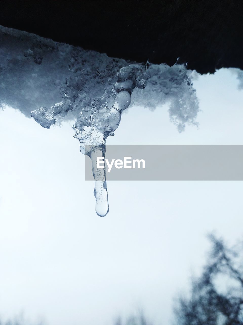 CLOSE-UP OF ICICLES AGAINST SKY DURING WINTER