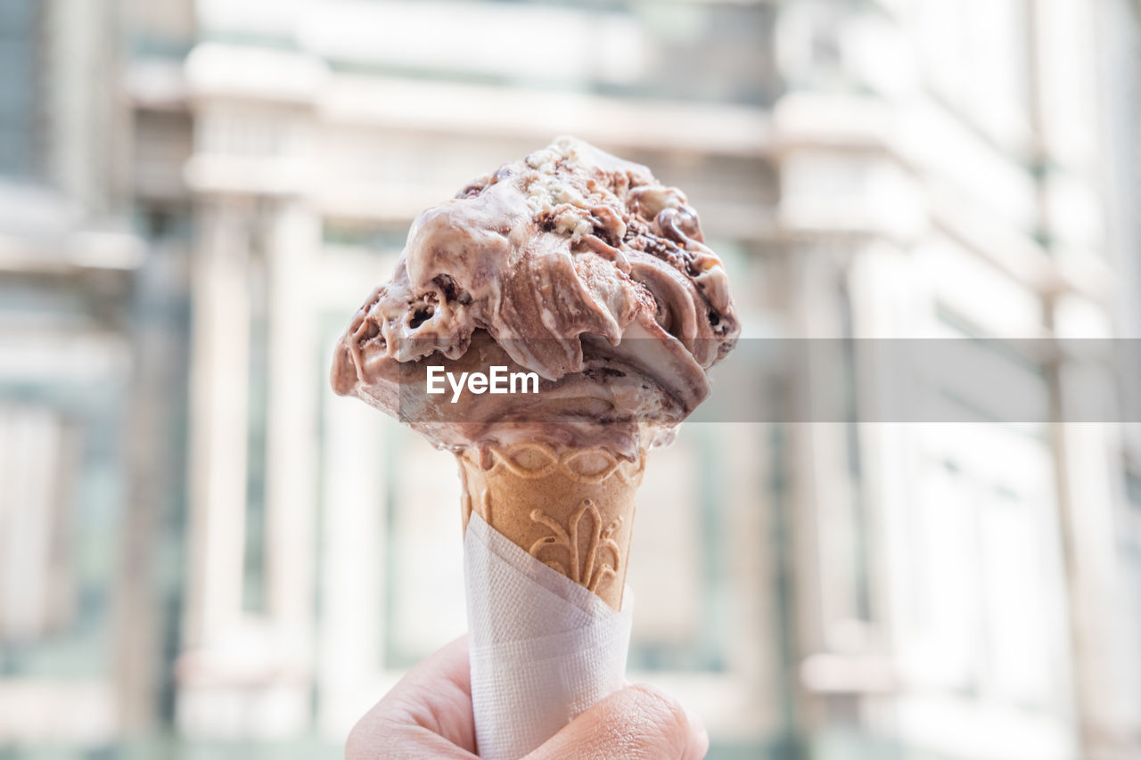 CLOSE-UP OF HAND HOLDING ICE CREAM OUTDOORS