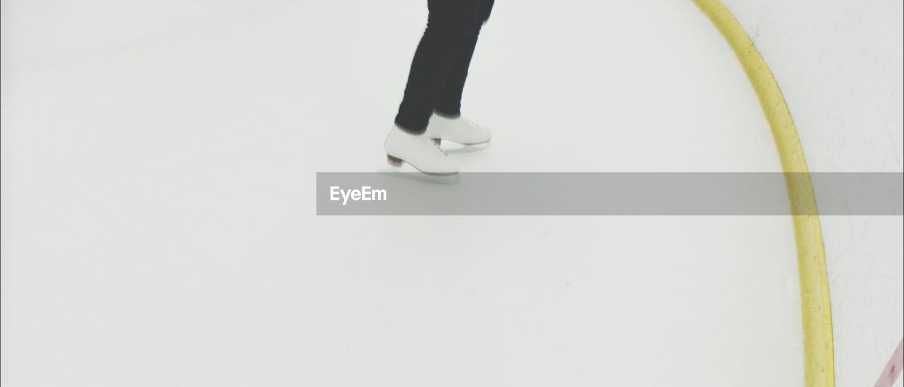 Low section of person skating at ice rink