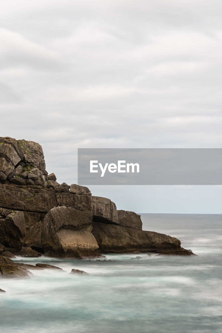 ROCK FORMATIONS ON SHORE AGAINST SKY