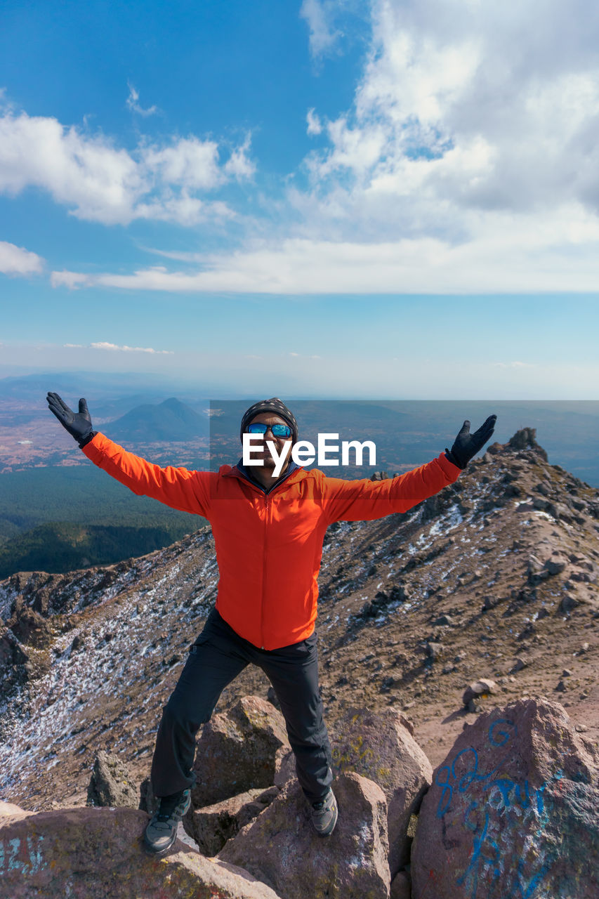 Portrait of man standing on rock against sky